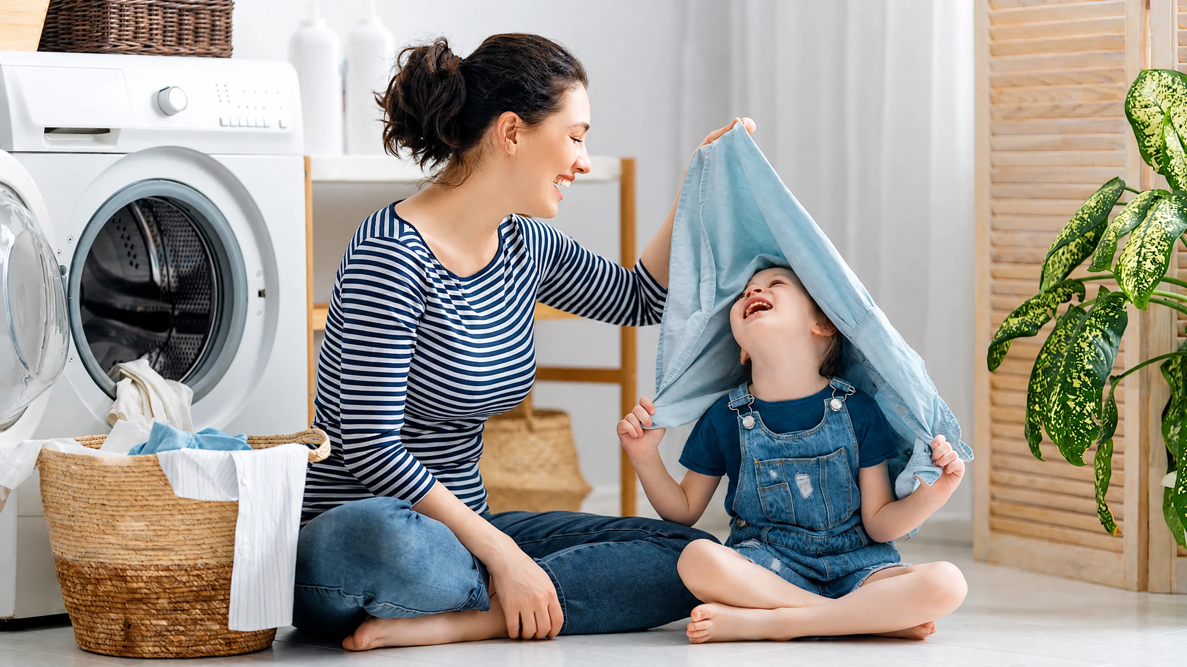 Parent and child enjoying time together beside a washing machine at home