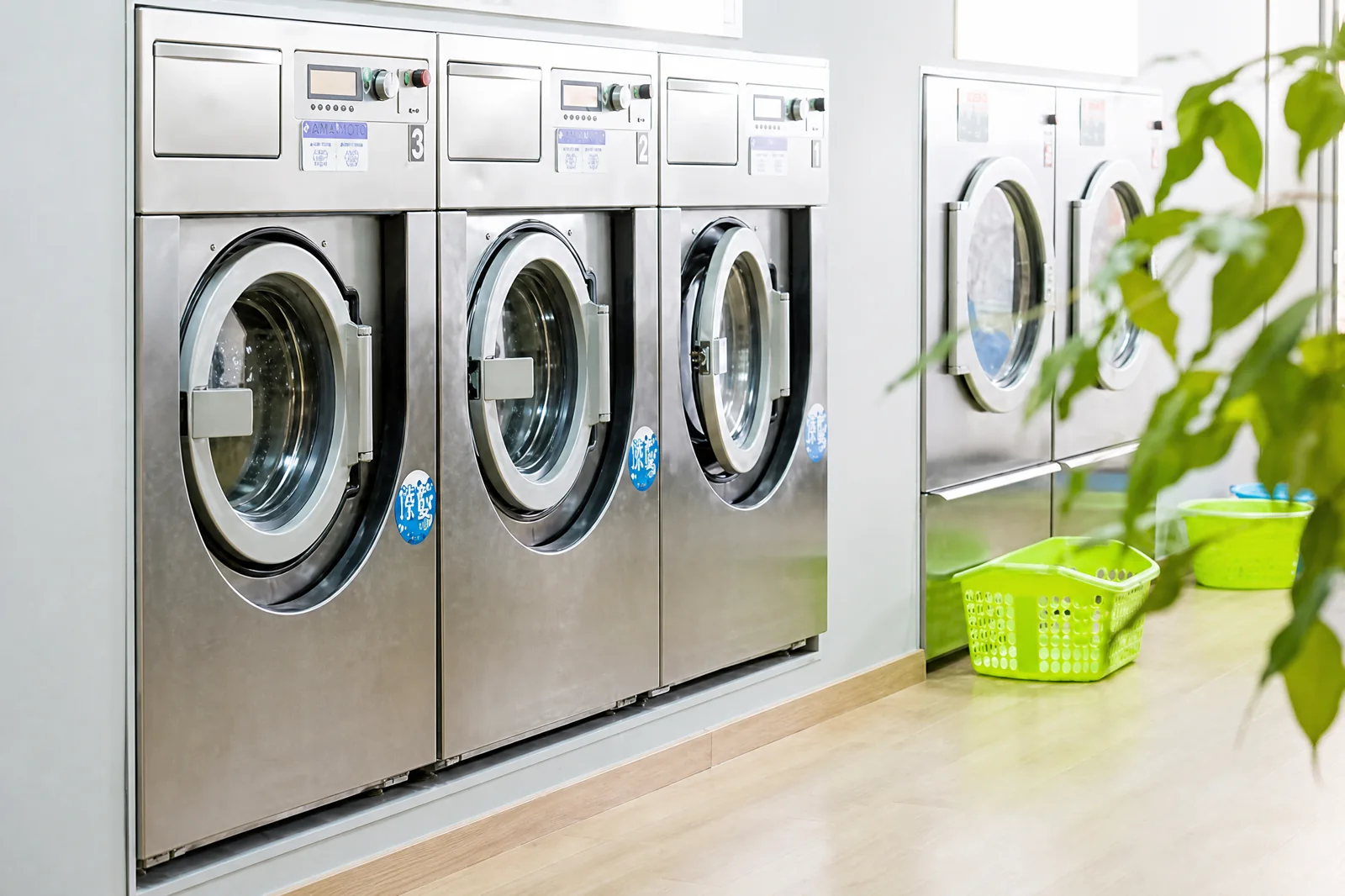 Technician inspecting large commercial washing machines in a commercial laundry